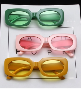 Close-up of rectangular chunky sunglasses in grass green, cherry pink, and mustard yellow