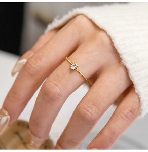 Detailed shot of an oval zircon ring with twisted gold rope band on a hand