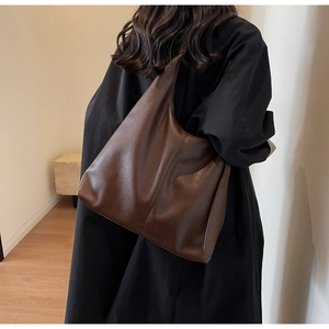 Detail of soft dark brown PU leather hobo bag showing texture and drape on a model