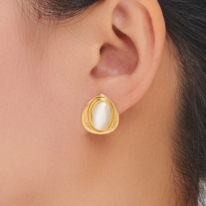 Close-up of teardrop gold stud earring with oval white opal stone on a female model