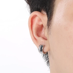 Macro shot of silver stainless steel hoop earrings with black and white crystals on ear