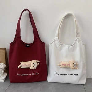 Detail of burgundy and cream canvas tote bags with plush 3D animal doll and embroidery