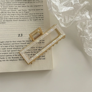 Detail of a French vintage golden rectangle hair claw clip on an open book