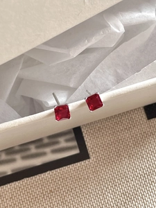 Macro shot of silver stud earrings with square red zircon in classic four-prong setting