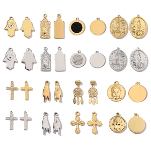 Macro view of mirror polished Hamsa, cross, and coin pendants in gold and silver steel