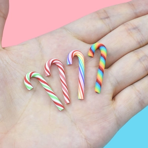 Miniature candy cane charms in hand showing small size for DIY crafts and decor