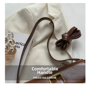 Close-up of vintage brown crossbody bag with gold buckle and smooth leather texture
