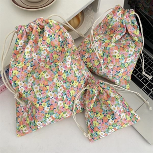 Three sizes of floral drawstring storage pouches shown in a lifestyle desk setting