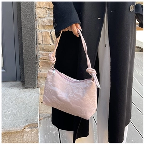 Detail of pink crinkled texture shoulder bag with decorative knotted handle on model