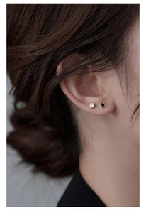 Close-up of minimalist gold square stud earrings with black and white zircon on ear lobe