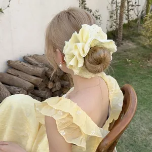 Pale yellow eyelet lace scrunchie shown on a high bun with elegant ruffled embroidery