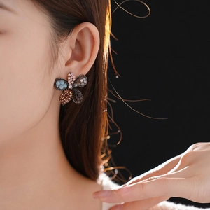 Elegant vintage flower stud earrings with colorful crystals worn by a model on dark background