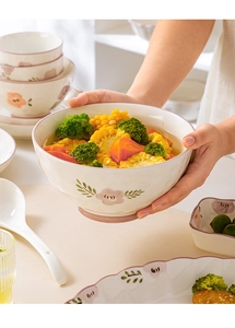 Detail of hand-held floral ceramic bowl with pink flowers and matching rim in a lifestyle setting