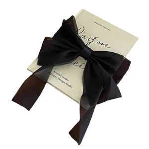 Elegant large black organza bow hair clip with ribbons on a French vintage book background