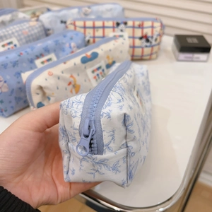 Detail von blauen Stoffmäppchen mit Blumen- und Cartoon-Mustern und Reißverschluss