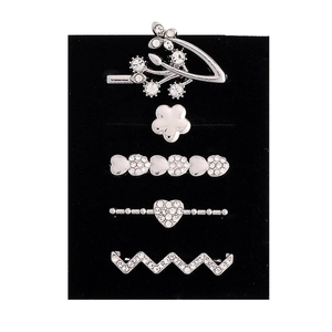 Close-up of five silver alloy hair pins with rhinestones on black velvet display