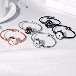 Close-up of minimalist quartz bangle watches in rose gold and silver on white fabric