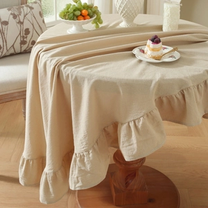 Detail of beige linen table cloth with ruffled edges on a wooden dining table