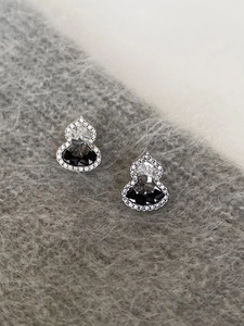 Macro shot of silver-tone gourd stud earrings with black gemstone and crystal pavé
