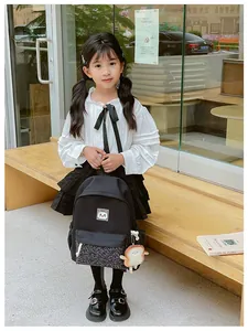 Detail of black kids backpack with cat patch, printed front pocket and plush toast charm