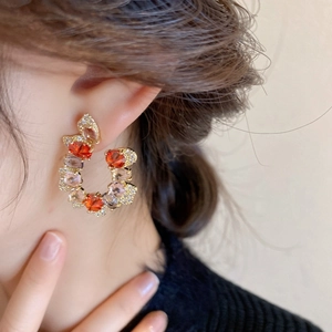 Vintage C-shaped drop earrings with colorful zircons worn on model's ear
