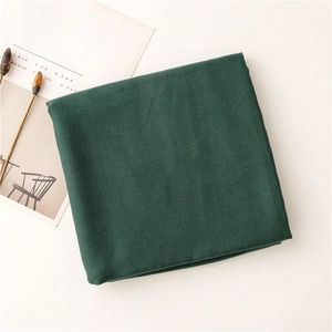 Detalle de bufanda de algodón y lino verde oscuro con textura tejida suave y capas