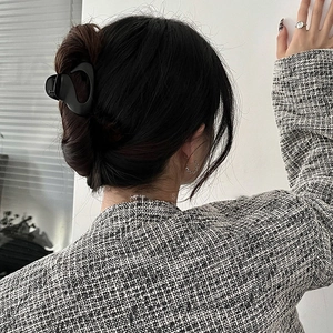 Close-up of a minimalist black claw clip holding hair in a stylish back view hairstyle