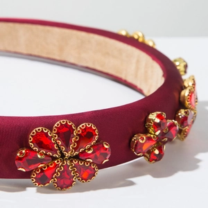 Détail macro du serre-tête en satin bordeaux avec des fleurs en cristaux sertis d'or