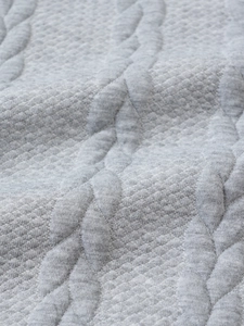 Detailed macro view of gray knitted fabric featuring cable knit and honeycomb texture