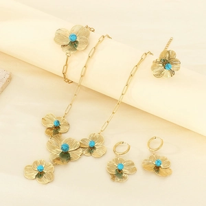 Close-up of golden four-leaf clover jewelry set with turquoise stones on elegant props