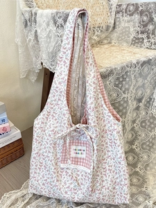 Floral canvas tote bag with pink checkered pocket and bow detail on a wooden chair