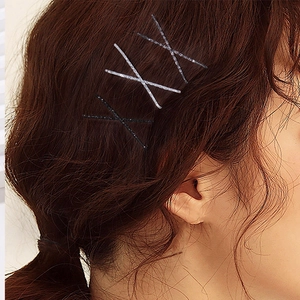 Glitter and black bobby pin set styled in X-shape on long brown hair for daily look