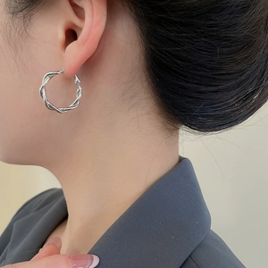 Detail of twisted silver hoop earring on model showing sleek metallic texture and design