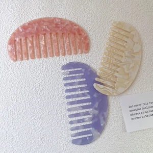 Three acetate hair combs with marble patterns in pink, beige, and purple colors