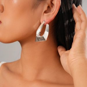Close-up of irregular geometric silver stud earring worn by a model for a modern look