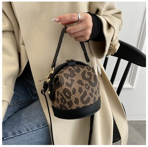 Leopard print cylinder bag detail with black leather handle and gold hardware on model