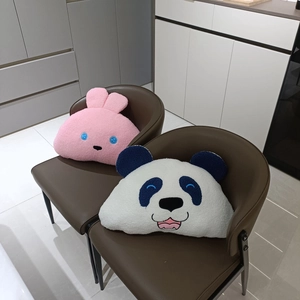 Plush cartoon panda and pink rabbit throw pillows displayed on a brown leather chair