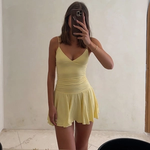 Detail of yellow V-neck mini dress showing ruched waist and A-line skirt in a mirror selfie