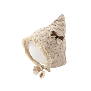 Beige knit baby bonnet with lace trim, bow decoration, and leaf-detail chin straps