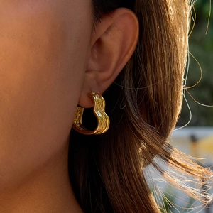 Close-up of 18K gold-plated stainless steel heart hoop earrings worn by a model