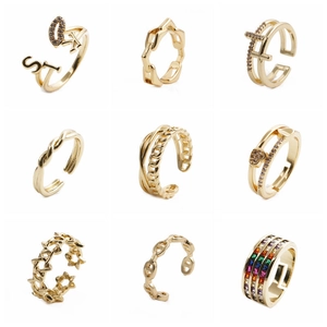 Collection of nine gold-plated fashion rings featuring star, cross, and shell designs