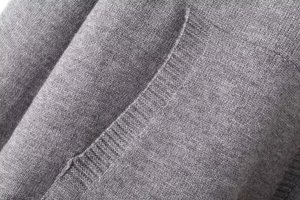 Macro shot of gray knitted texture and side pocket detail on a casual hooded sweater