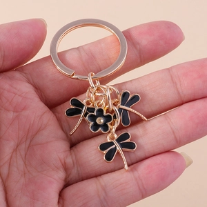 Detailed view of creative gold keychain featuring black enamel dragonflies and flower charm