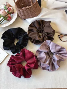 Set of four satin scrunchies in black, coffee, burgundy and lilac displayed with props