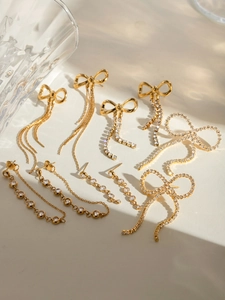 Detailed view of gold bow earrings and rhinestone tassels on textured background