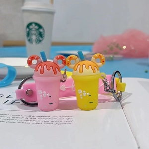 Detail of pink and yellow milk tea cup keychains with donut ears and silicone wristlet