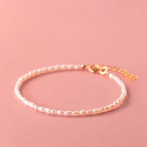 Detailed macro view of natural freshwater pearls with gold clasp on pink surface