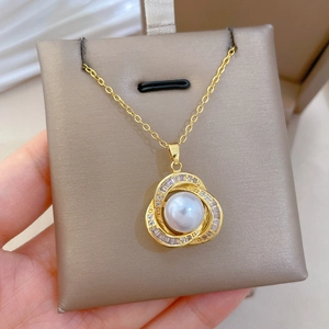 Close-up of golden bird nest necklace with a large pearl and sparkling layered diamonds