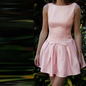 Detail of pink satin mini dress featuring a sleeveless round neck and waist bow decoration