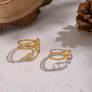 Minimalist geometric safety pin ring in gold and silver finish on stone tray